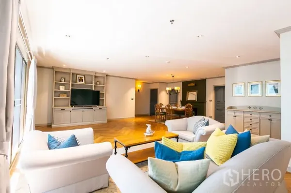 อพาร์ทเมนท์ ให้เช่าในWatthana, Bangkok - ห้องนั่งเล่นและรับประทานอาหารแบบโอเพ่นสเปซ มีชั้นบิลต์อิน โซฟาหมอนสีสัน และพื้นไม้ก้างปลา