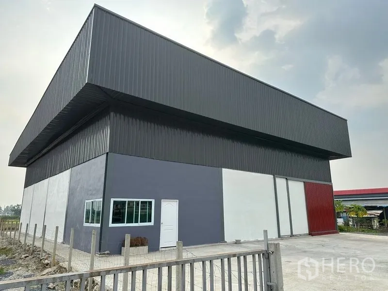 Warehouse for rent in Bang Bua Thong, Nonthaburi - Modern steel‑clad warehouse exterior with high eaves, wide sliding loading doors and a concrete yard in Bang Bua Thong, Nonthaburi.