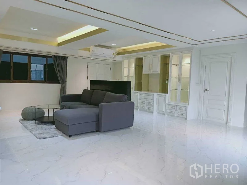 Condominium for  in Watthana, Bangkok - Living area with L-shaped sofa, display cabinets and recessed lighting.