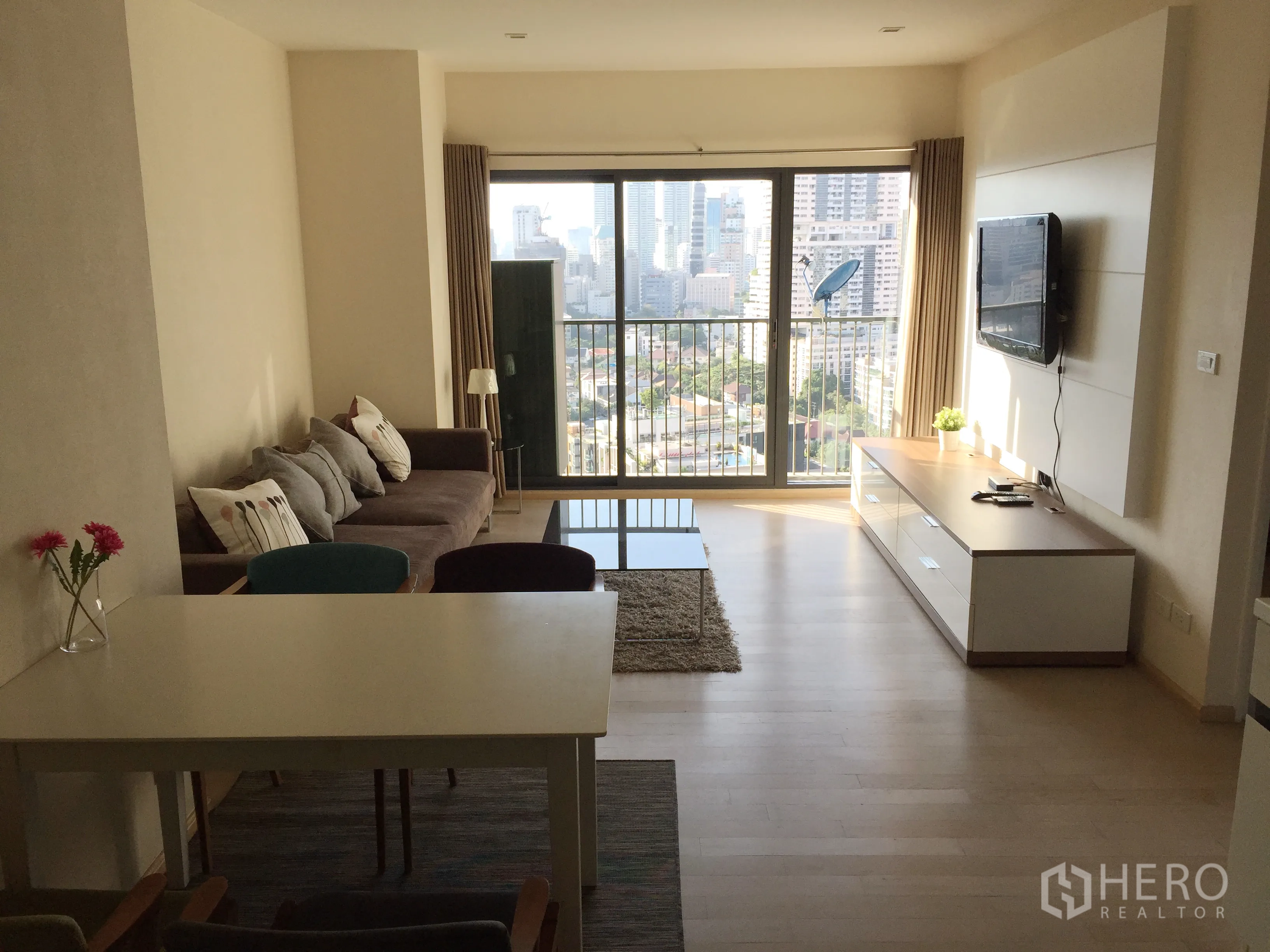 คอนโด ให้เช่าในKhlong Toei, Bangkok - ห้องนั่งเล่นและรับประทานอาหารแบบเปิดโล่งพร้อมโซฟา โต๊ะ และวิวเมืองจากระเบียง