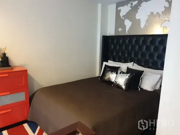 公寓 出租在Khlong Toei, Bangkok - 卧室配软包床头、世界地图墙饰与红色斗柜。