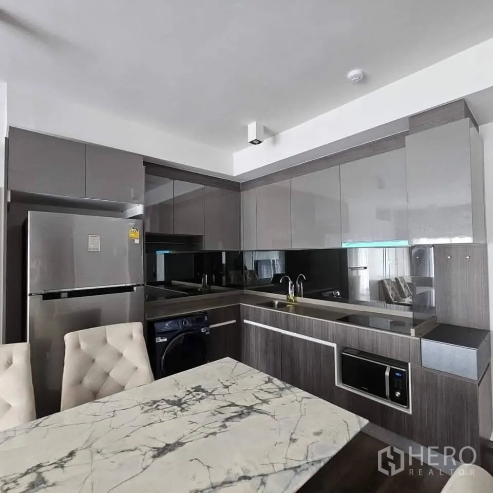 公寓 for rent in Huai Khwang, Bangkok - 现代L型厨房，亮面柜、洗槽、灶台、微波炉和洗衣机。