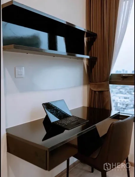 Condominium for sale in Huai Khwang, Bangkok - Built-in black desk and floating shelves by the window, creating a home office with views.