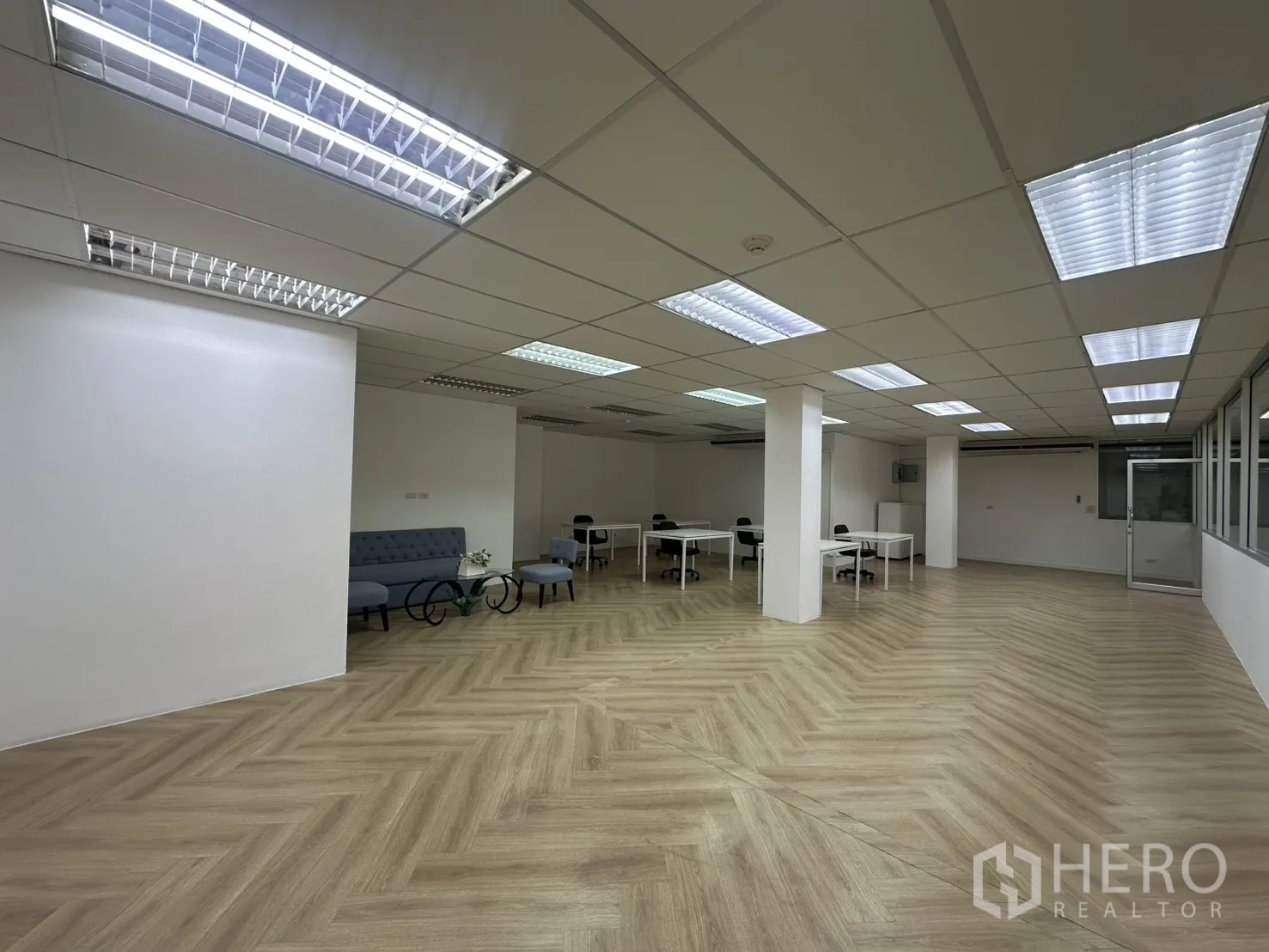 ออฟฟิศ for rent in Pathum Wan, Bangkok - มุมมองพื้นที่ทำงานโล่งพร้อมโซฟา โต๊ะกลาง เสากลางห้อง และไฟฟลูออเรสเซนต์