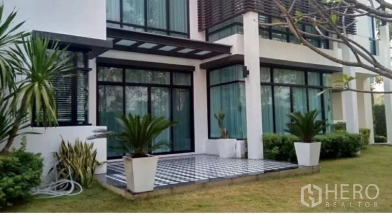 Detached House for sale in Saphan Sung, Bangkok - Ground-floor terrace with black and white checkerboard tiles and potted palms beside tall windows.