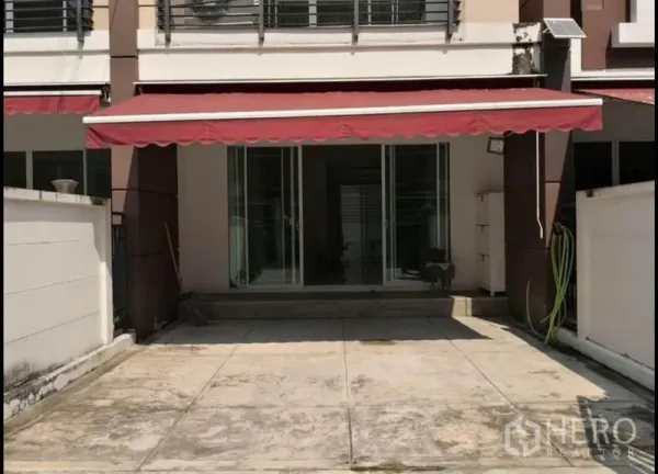 Townhouse for sale in Rat Burana, Bangkok - Townhouse front with red awning, sliding glass doors, and a paved carport in Rat Burana.