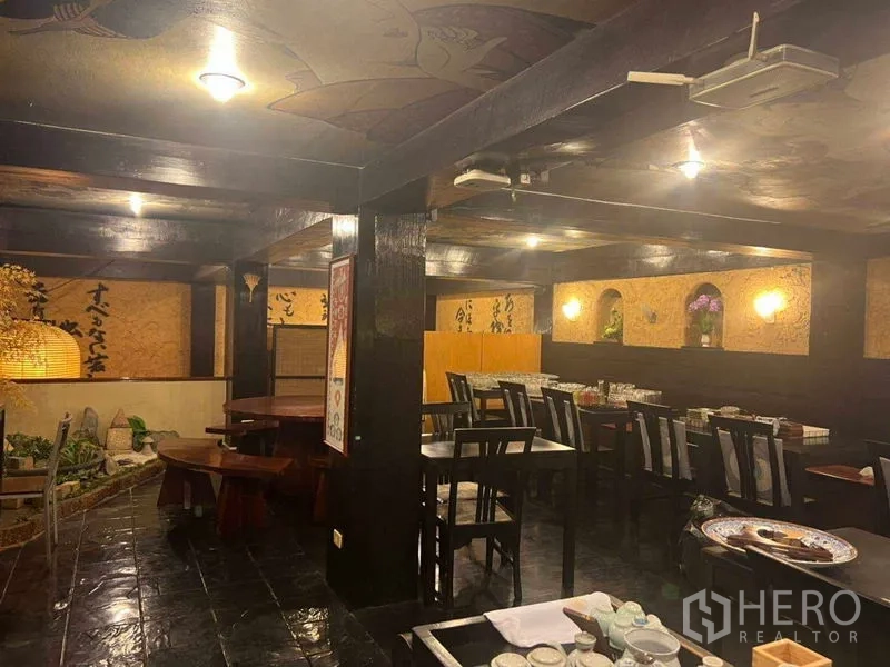 อาคารพาณิชย์ ให้เช่าในKhlong Toei, Bangkok - โถงรับรองกว้างคานไม้สีเข้ม พร้อมโต๊ะหลายชุดและไฟส่องสว่างตามผนัง