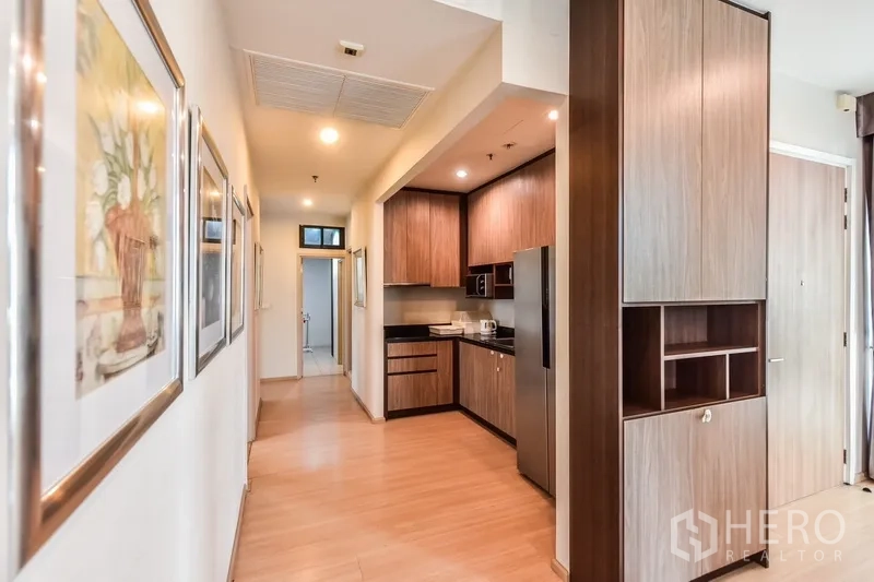 Condominium for rent or sale in Huai Khwang, Bangkok - Separate kitchen with wood cabinetry, black countertops, and stainless-steel refrigerator.