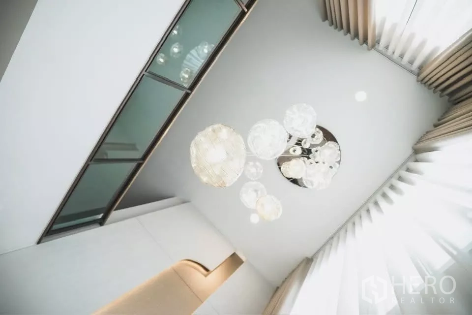 Detached House for rent in Bang Phli, Samut Prakan - Artistic view of a modern pendant chandelier on the double-height ceiling with tall curtains.