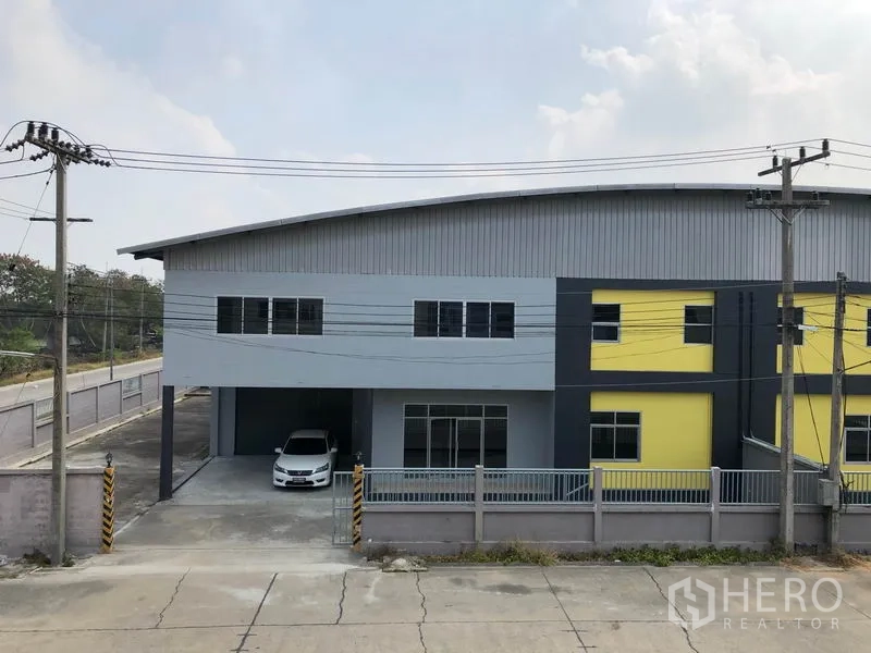 Factory for rent in Lat Lum Kaeo, Pathum Thani - Street-facing view of gated factory with parking apron and a wide driveway.