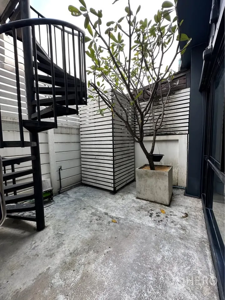 Townhouse for rent in Pak Kret, Nonthaburi - Private patio with spiral staircase, white slatted fence, and potted tree.