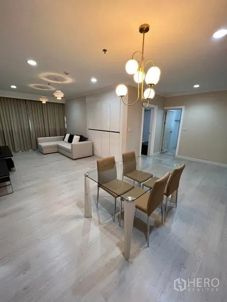 Condominium for sale in Sathon, Bangkok - Open-plan living and dining room with sofa, built-in storage, and warm ceiling lights.