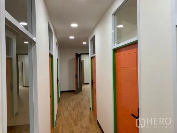 Office Space for rent in Khlong Toei, Bangkok - Well-lit corridor with multiple private offices featuring orange doors and transom windows.