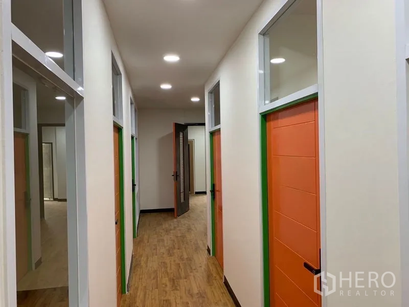 Office Space for rent in Khlong Toei, Bangkok - Well-lit corridor with multiple private offices featuring orange doors and transom windows.
