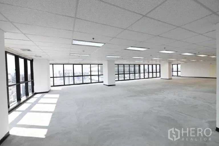 Office Space for rent in Huai Khwang, Bangkok - Sunlit office interior featuring panoramic glazing on two sides, pillars and a suspended ceiling.