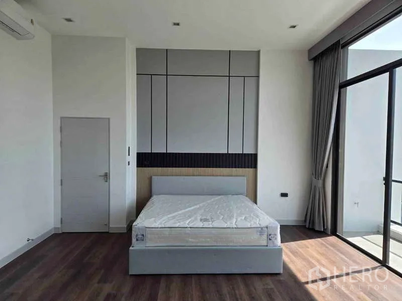 บ้าน ให้เช่าในBang Phli, Samut Prakan - ห้องนอนกว้าง ผนังตกแต่ง เตียงคู่ และประตูกระจกเต็มบานเปิดสู่ระเบียง