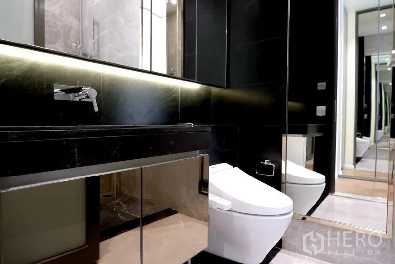 公寓 出租在Pathum Wan, Bangkok - 现代浴室，黑色石材台面、镜面灯带与智能马桶