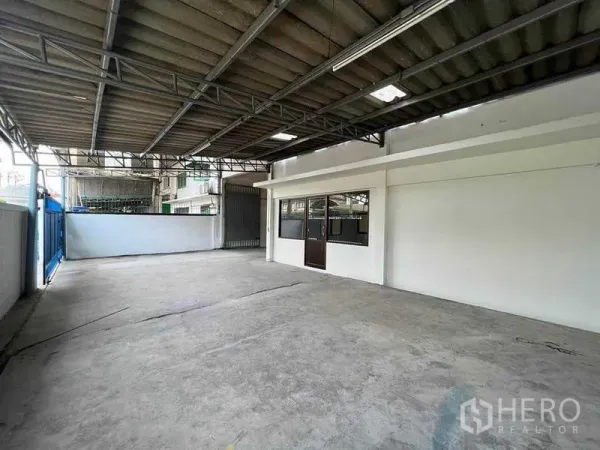 Warehouse for rent in Khlong Toei, Bangkok - Covered loading yard with metal roof, concrete floor, and direct access to office windows.
