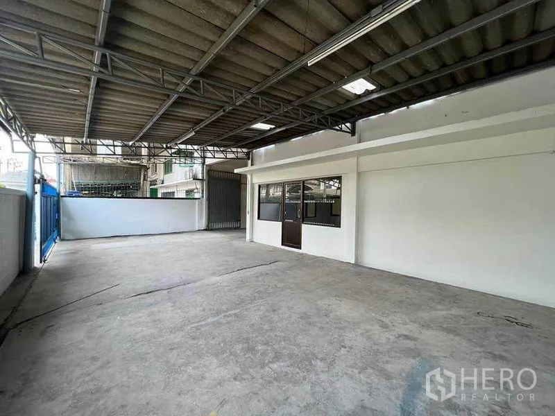 Warehouse for rent in Khlong Toei, Bangkok - Covered loading yard with metal roof, concrete floor, and direct access to office windows.