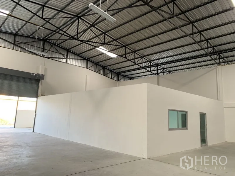 Warehouse for rent in Samut Prakan - Warehouse bay with internal office block, high roof structure and roller shutter access.