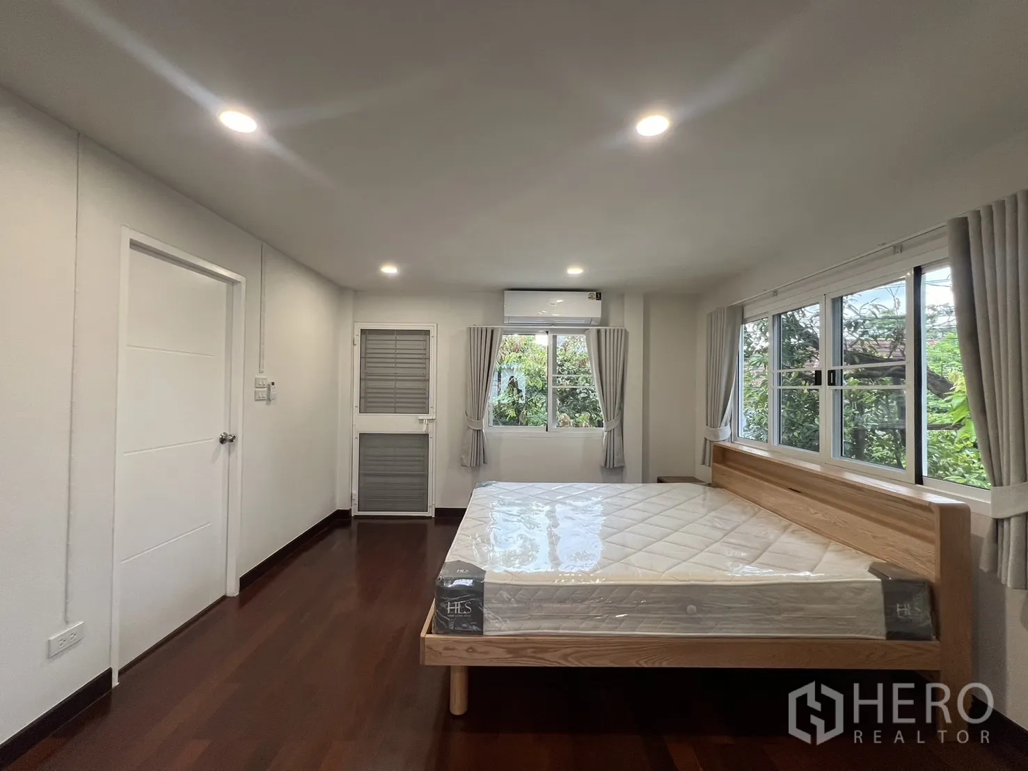 Detached House for rent in Saphan Sung, Bangkok - Bright upstairs bedroom with windows on two sides and small balcony door.