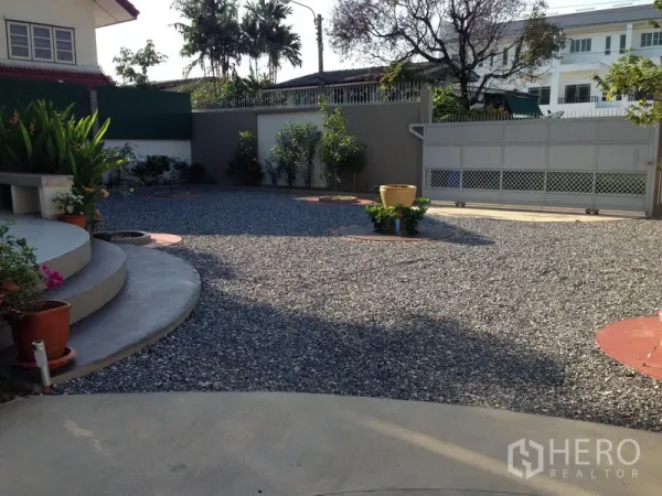 独立式住宅 出售在Phra Khanong, Bangkok - 宽阔的碎石庭院与大门，可停放多辆车，设有花盆与弧形台阶。