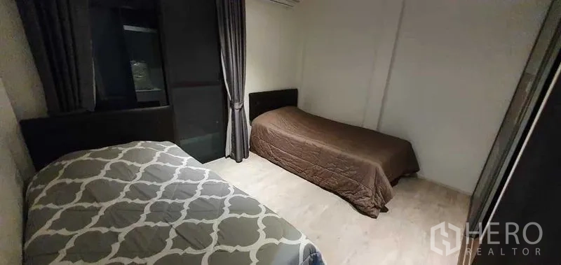 独立式住宅 出租在Prawet, Bangkok - 卧室内两张单人床，浅色木地板与窗帘