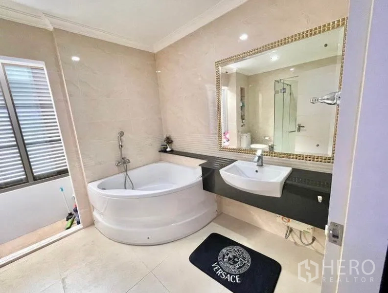 独立式住宅 出租在Prawet, Bangkok - 浴室设转角浴缸、独立玻璃淋浴与大镜面。