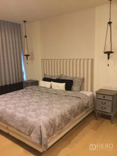 คอนโด ให้เช่าในPhaya Thai, Bangkok - ห้องนอนบรรยากาศสงบ หัวเตียงหุ้มผ้า ชุดเครื่องนอนสีเทา โคมแขวน และโต๊ะข้างเตียง