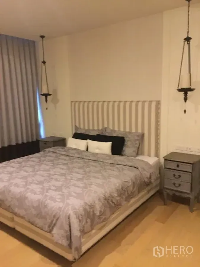 คอนโด ให้เช่าในPhaya Thai, Bangkok - ห้องนอนบรรยากาศสงบ หัวเตียงหุ้มผ้า ชุดเครื่องนอนสีเทา โคมแขวน และโต๊ะข้างเตียง