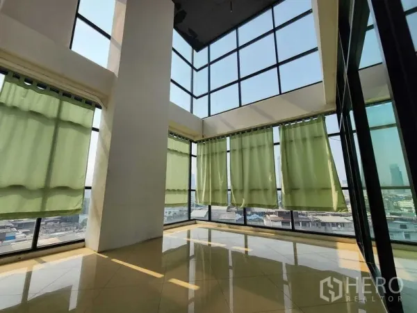 Office Space for rent in Yan Nawa, Bangkok - Bright corner room with tall glass walls and green blackout curtains.