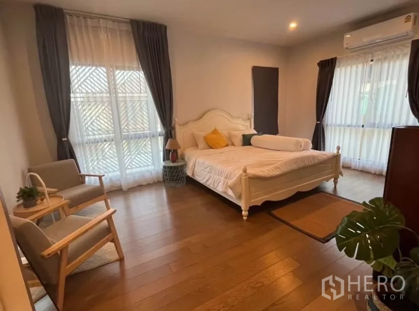 Detached House for rent in Prawet, Bangkok - Second bedroom with classic bed, seating nook and double-aspect windows.