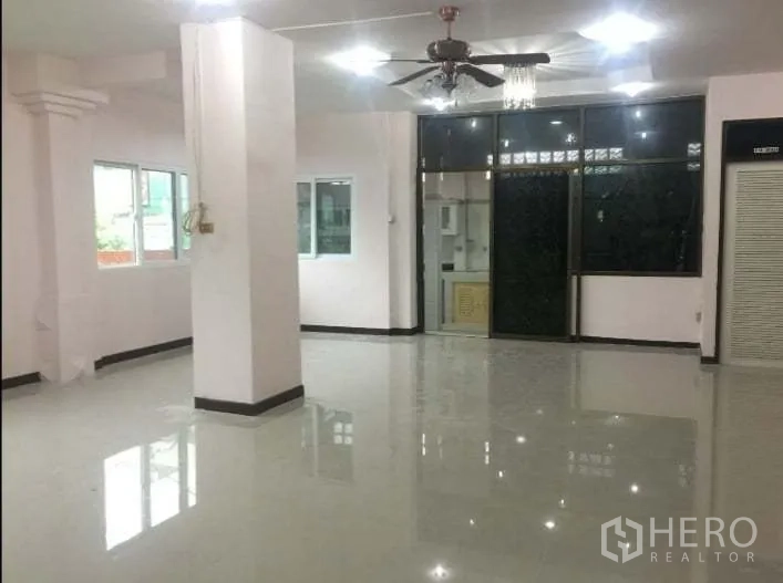 บ้าน ให้เช่าในChatuchak, Bangkok - โถงรับแขกขนาดใหญ่มีเสา พัดลมเพดาน และประตูกระจกกั้นโซนครัว