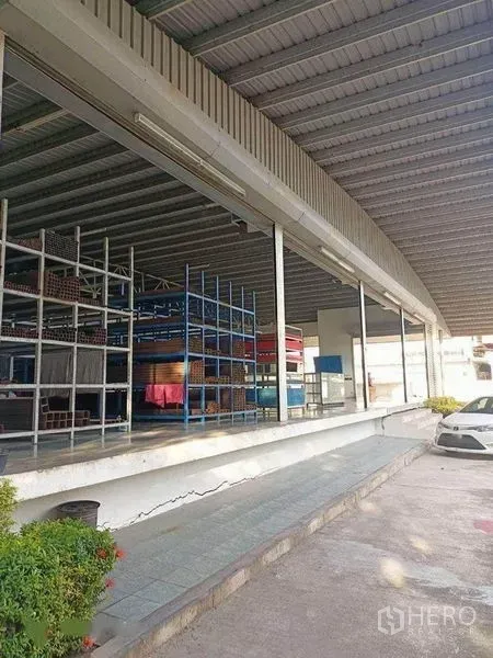 Warehouse for rent in Bang Phli, Samut Prakan - Raised loading platform with metal shelving beneath a deep all-weather canopy.