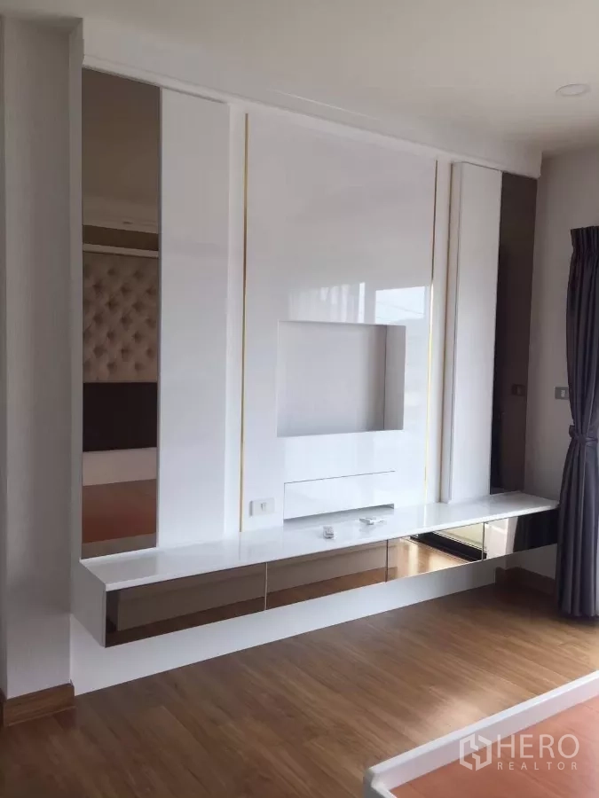 Detached House for rent in Samut Prakan - Bedroom feature wall with floating TV console and glossy white finish.