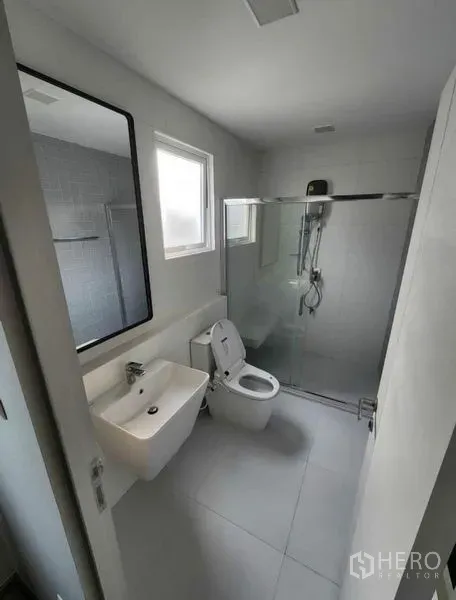 Detached House for rent in Prawet, Bangkok - Bright bathroom with glass-enclosed shower, toilet, vanity basin, and windows for ventilation.