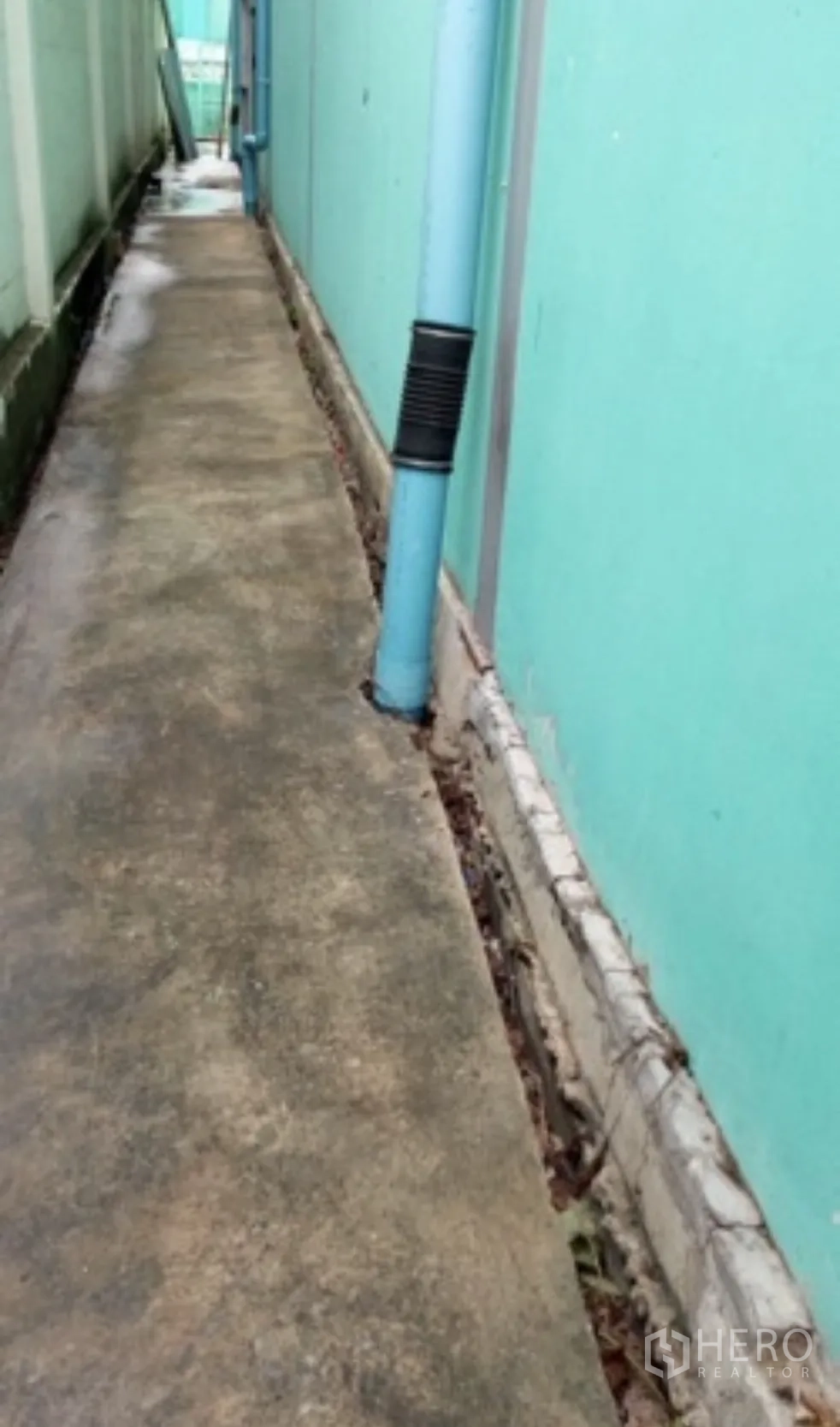 โกดัง for rent in Mueang Nonthaburi, Nonthaburi - ทางเดินแคบด้านข้างอาคาร มีท่อพีวีซีสีน้ำเงินและพื้นคอนกรีตขนาบผนังโกดัง