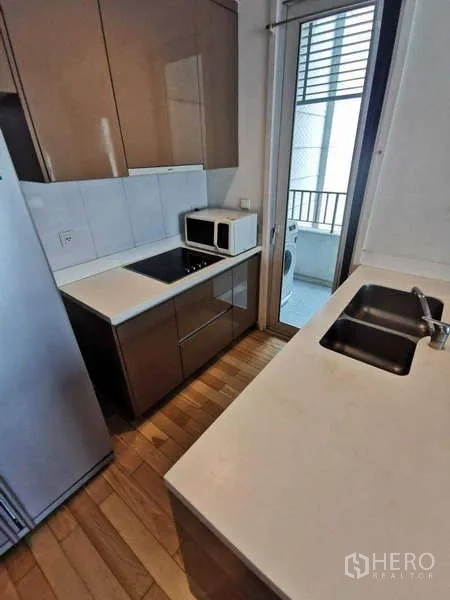 公寓 出租在Khlong Toei, Bangkok - 厨房岛台与双槽水槽，面向灶台与储物柜。