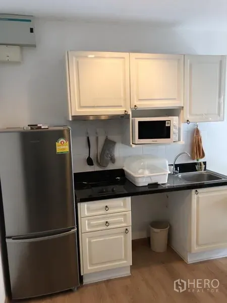 คอนโด ให้เช่าในPathum Wan, Bangkok - ครัวขนาดกะทัดรัด ตู้สีขาว ท็อปหินสีดำ อ่างล้างจาน ไมโครเวฟ และตู้เย็นสแตนเลส