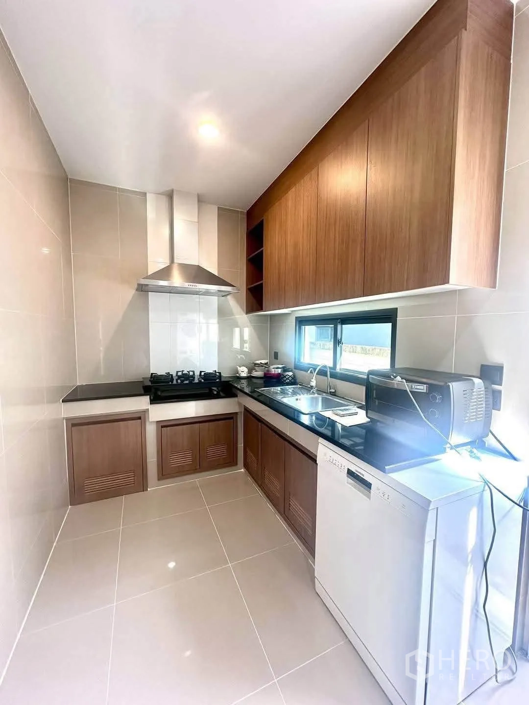 Detached House for rent in Bang Kapi, Bangkok - Modern kitchen with gas hob, range hood, wood cabinets and dishwasher.