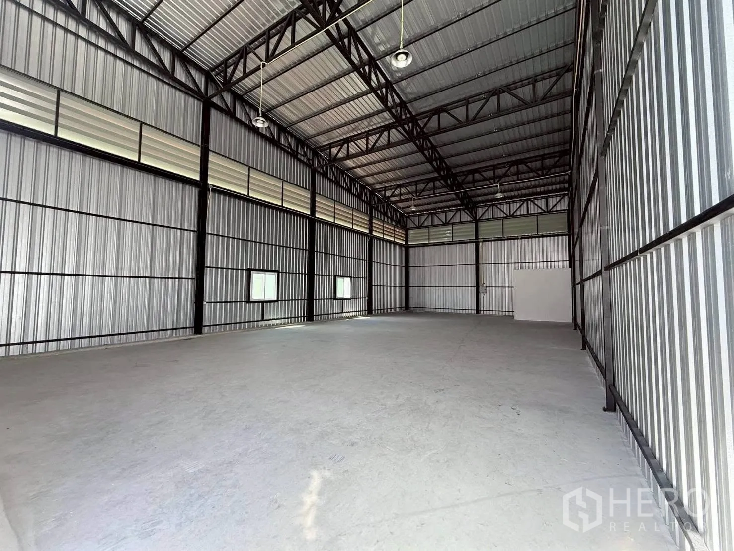 Warehouse for rent in Bang Phli, Samut Prakan - Open storage hall showing overhead lighting, ventilation panels, and concrete flooring.