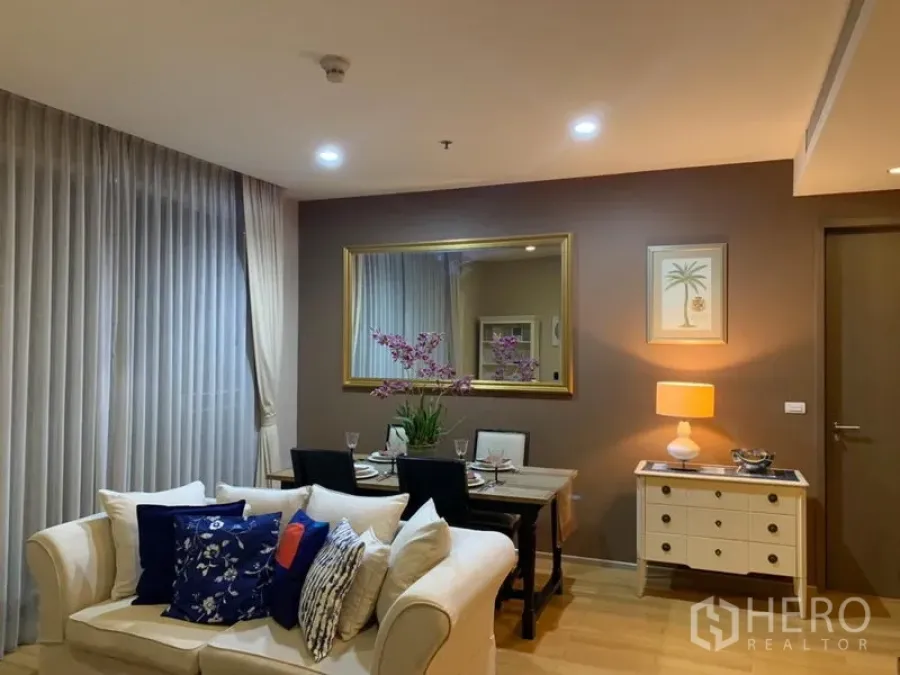 คอนโด ให้เช่าในWatthana, Bangkok - พื้นที่นั่งเล่นและรับประทานอาหารโทนอบอุ่น โซฟาสีครีม โต๊ะทานข้าว กระจกบานใหญ่ และแสงไฟนุ่มนวล