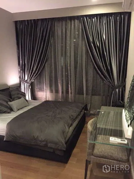 Condominium for rent in Bang Rak, Bangkok - Bedroom with double bed, dark drapes and glass work desk on hardwood floor.