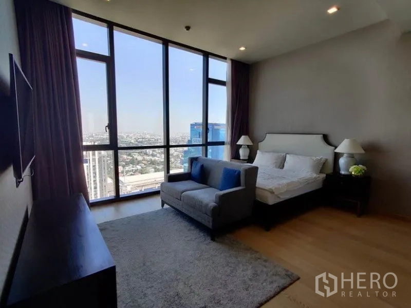 Condominium for rent in Watthana, Bangkok - Guest bedroom with sofa seating area, large windows, and wide city outlook.