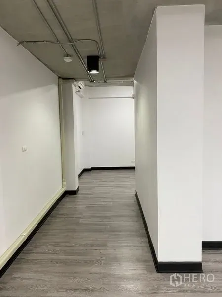 Office Space for rent - Long corridor inside the office showing grey laminate floors and visible ceiling piping for a contemporary look.