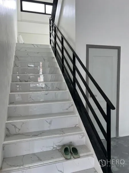 货栈 出租在Bang Sao Thong, Samut Prakan - 铺大理石纹瓷砖的楼梯，黑色扶手通往上层