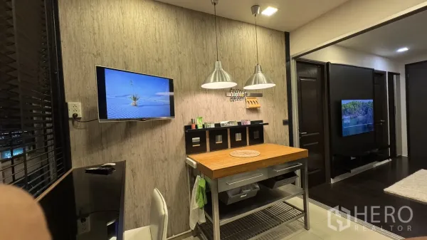 公寓 出租或出售在Khlong Toei, Bangkok - 用餐角落，墙挂电视、金属吊灯与木质操作岛台。