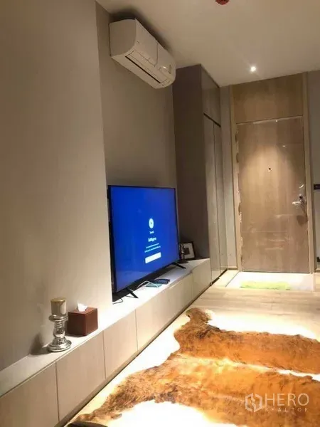 Condominium for rent in Watthana, Bangkok - Living area with low TV console, split air-conditioner and entrance door in a cozy condominium.