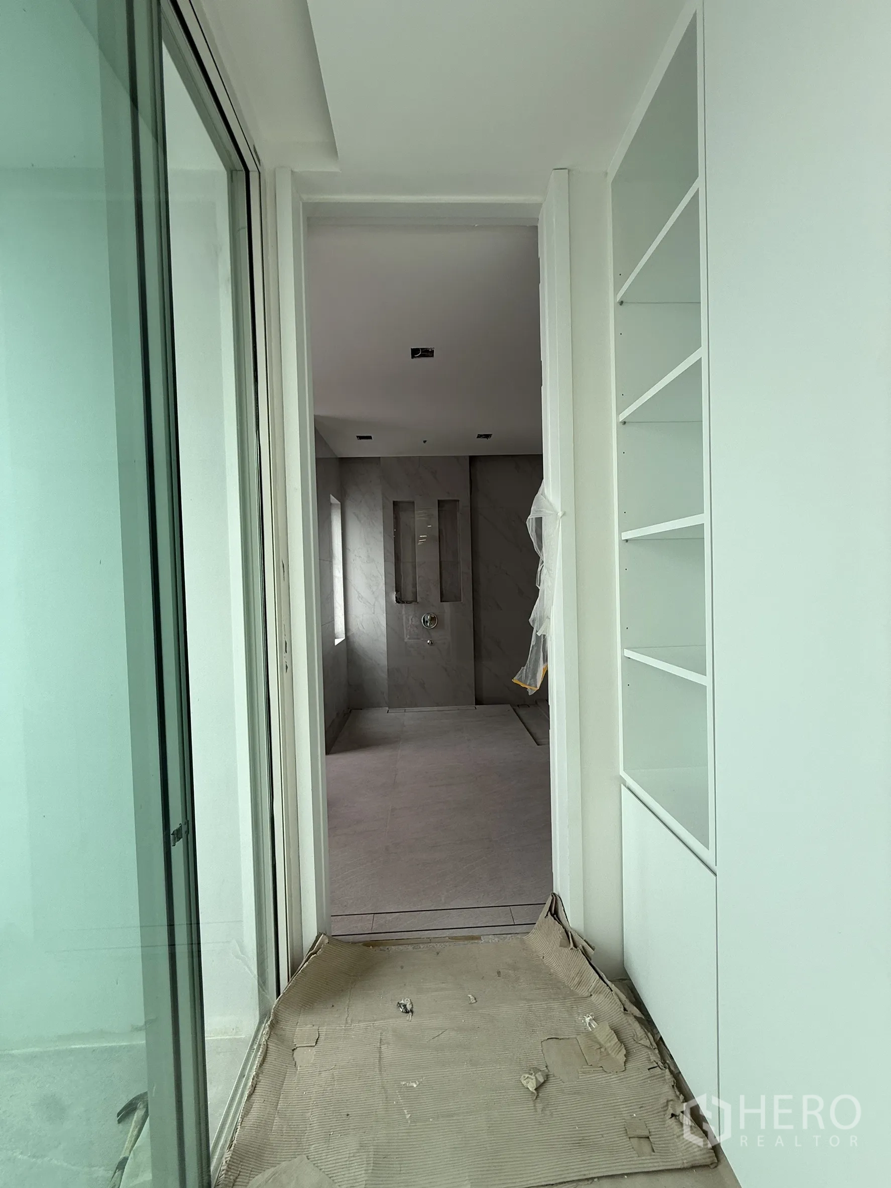 Detached House for sale in Bang Phli, Samut Prakan - Passage with shelving looking into large marble-tiled bathroom.