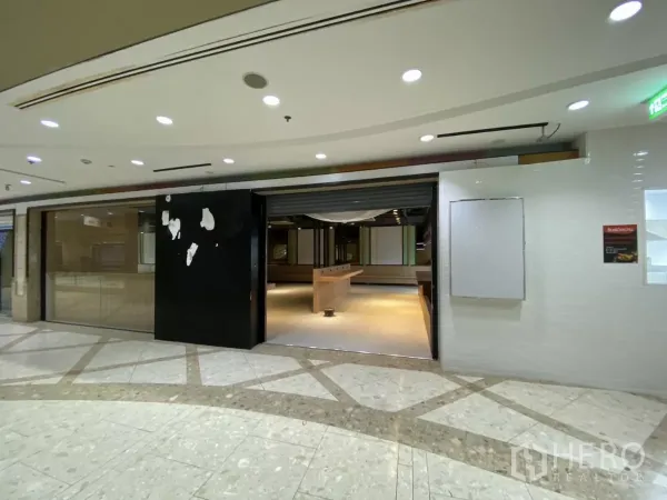 零售空间 出租 - 卷帘开启的入口，室内吧台与灯光可见